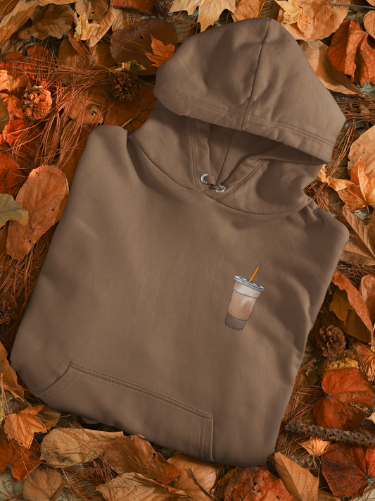 Brown hoodie with a coffee cup design on a bed of autumn leaves