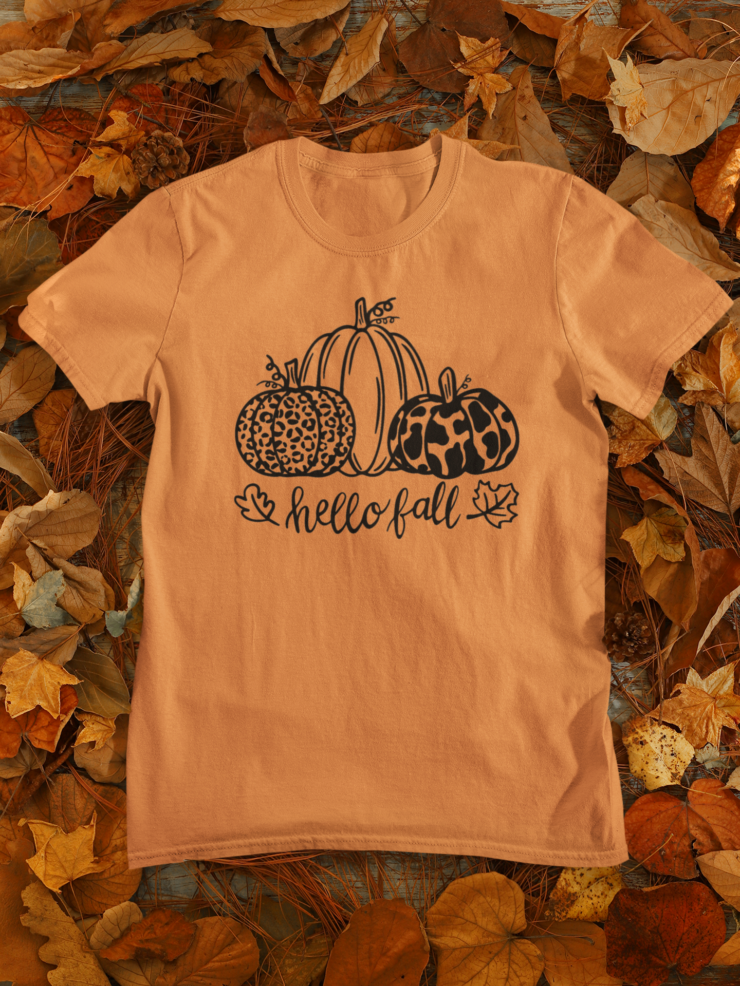 Hello Fall Pumpkin T-Shirt - front view on a background of leaves