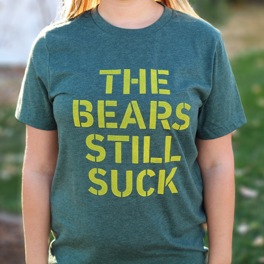 The Bears Still Suck - T-Shirt in forest green with yellow writing in a bold font on the front - this is an image of the front of the t-shirt on a model - up close view.