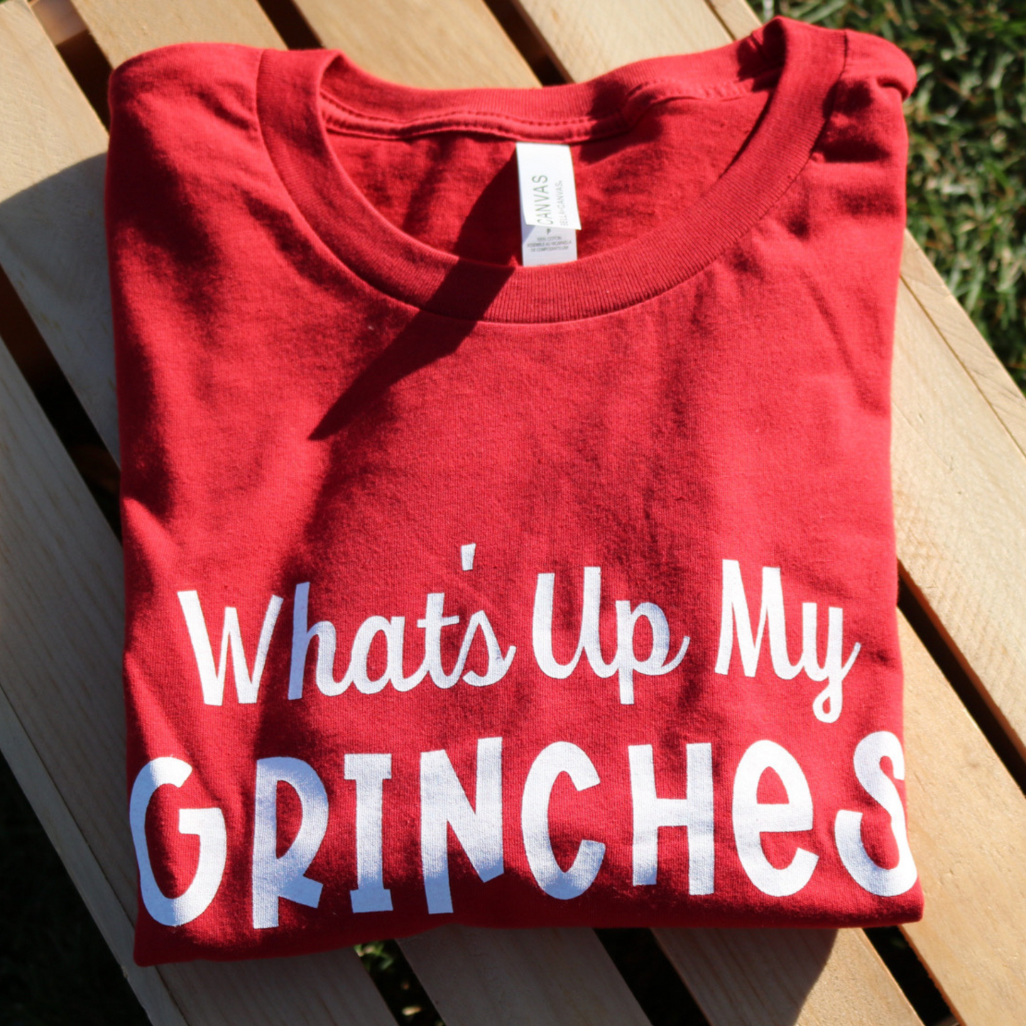 What's Up My Grinches? - T-Shirt - folded front view - stylized on a wooden crate in a grassy area.