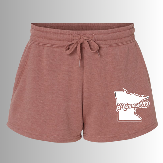 Minnesota Shorts in a light pink/red color with the state of minnesota emblem on the front right corner of the short with minnesota through it. This is the front view of the short on a gray to white gradient background.