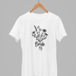 Floral Bride T-Shirt in white. The front has a bouquet of dainty flowers with the word "bride" written in the stems in a black design. This is the front view of the shirt hanging on a wooden hanger, hanging on a metal clothing rack with a gray plain background.