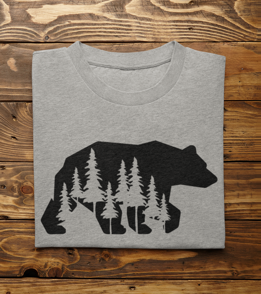 Woodsy Bear Silhouette - T-Shirt in gray with the bear in black and pine trees cut out of the bear design, folded laying on a wooden background