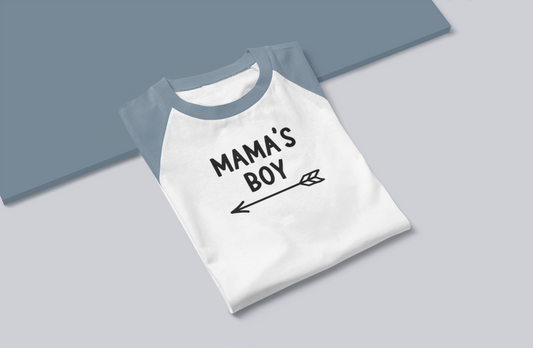 Mama's Boy - Three Quarter Baseball T-Shirt. Sleeves in a Heather light blue on the sleeves with a white base. Mama's Boy is in black with an arrow below it pointing to the left. This is the front view of the shirt - folded on a blue and gray background.