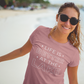 Life Is Better By The Lake - T-Shirt in Mauve with white writing  on a model at the lake with sunglasses on smiling