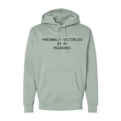 Light green hoodie with text 'PERSONALLY VICTIMIZED BY MY MIGRAINES' on a white background